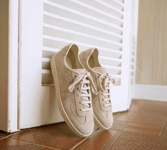 Pair of sand suede sneakers beside a shuttered door