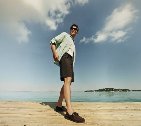Man on a jetty in a linen shirt and brown suede moccasins