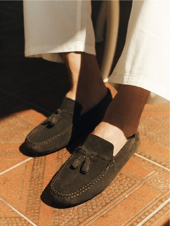 Dark suede tassel loafer on a tiled floor